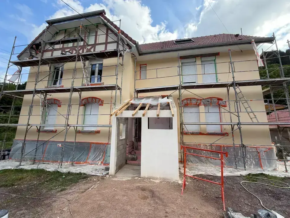 Façade en cours d'enduit, auvent en construction